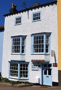 picture of 3 story bulding painted white with light blue door and window frames
