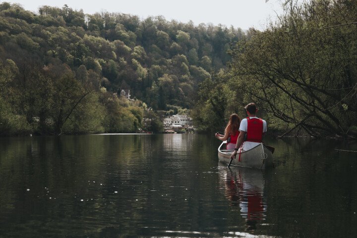 picture of two people in red vests on canoe facing away
