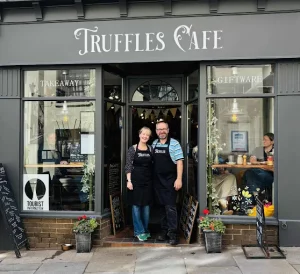 picture of shopfont with painted grey at the front and man and woman standing in doorway