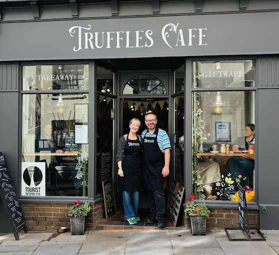 picture of shopfont with painted grey at the front and man and woman standing in doorway