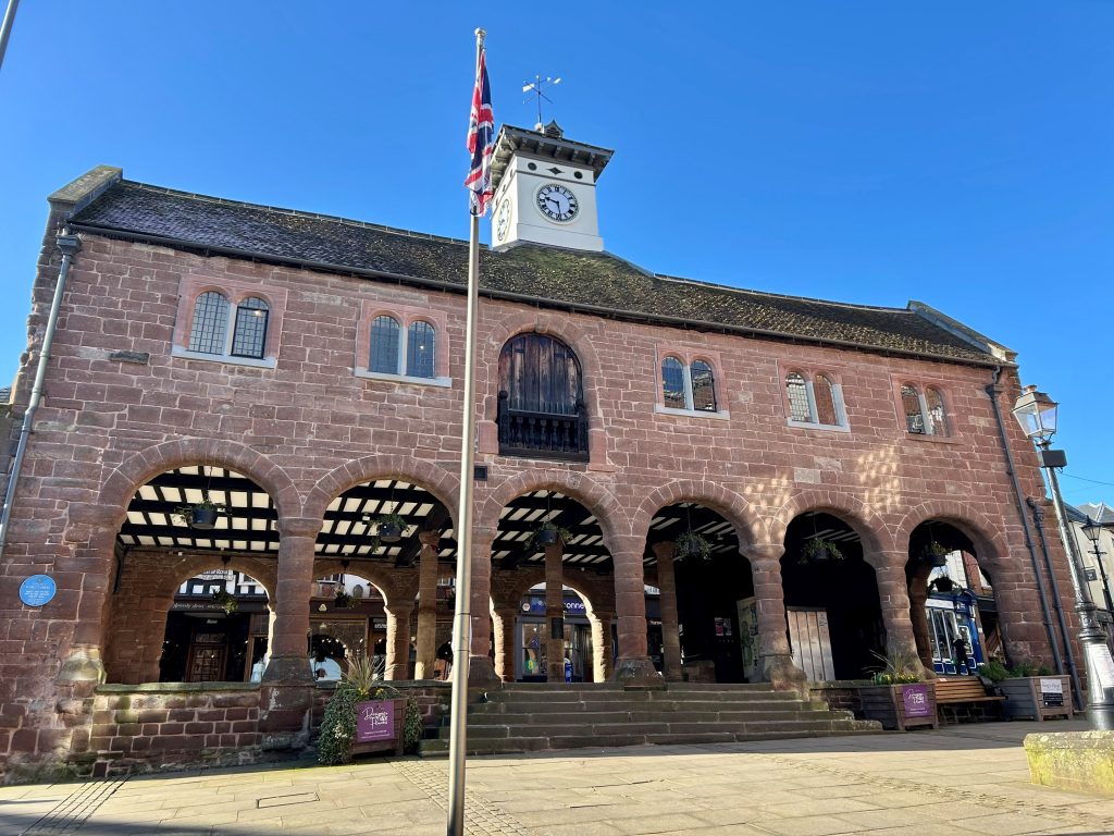 Picture of brick building, open underneath with arches, in the sun