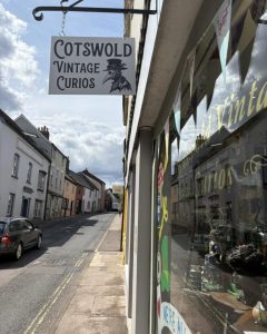 Picture of handing shop sign from beelow, glass to thee right with sticker saying business name
